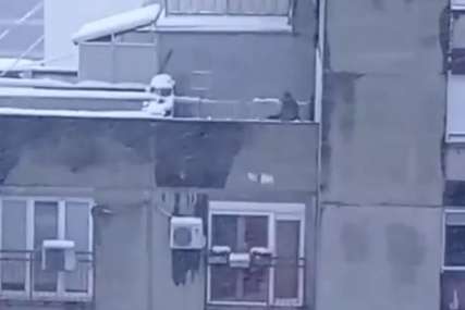 Sa krova zgrade ČISTI ZALEĐENI SNIJEG, a ni da pogleda da li će nekom pasti na glavu (VIDEO)