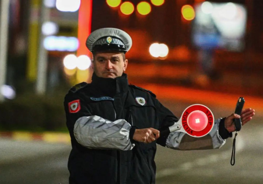 policajac drži znak stop