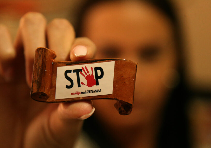 žena pokazuje bedž s natpisom "Stop nasilju nad ženama"