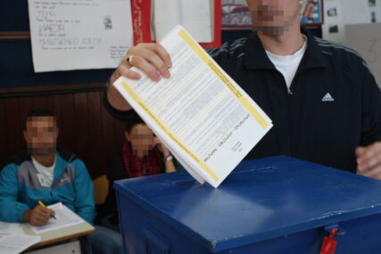glasač ubacuje izborni listić u kutiju