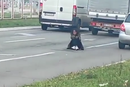 Žena sjedi između 2 saobraćajne trake i prosi "Dobija batine od muža ako ne donese dovoljno novca" (VIDEO)