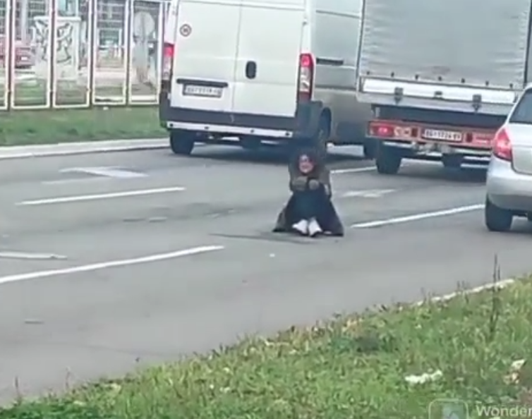Žena sjedi između 2 saobraćajne trake i prosi "Dobija batine od muža ako ne donese dovoljno novca" (VIDEO)