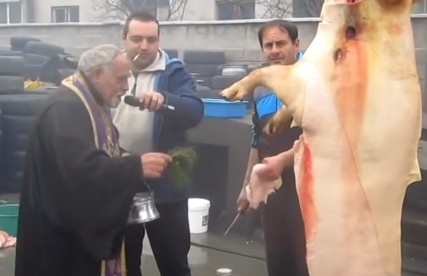 Snimak izazvao buru komentara: Sveštenik blagosilja svinjokolj na autopraonici (VIDEO)