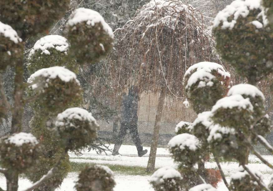 čovjek hoda dok pada snijeg