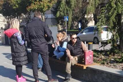 Miljana Kulić sjedi na klupi, pored nje neki ljudi