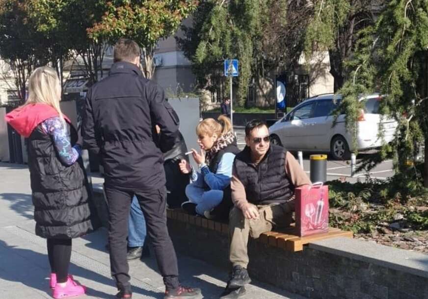 Miljana Kulić sjedi na klupi, pored nje neki ljudi