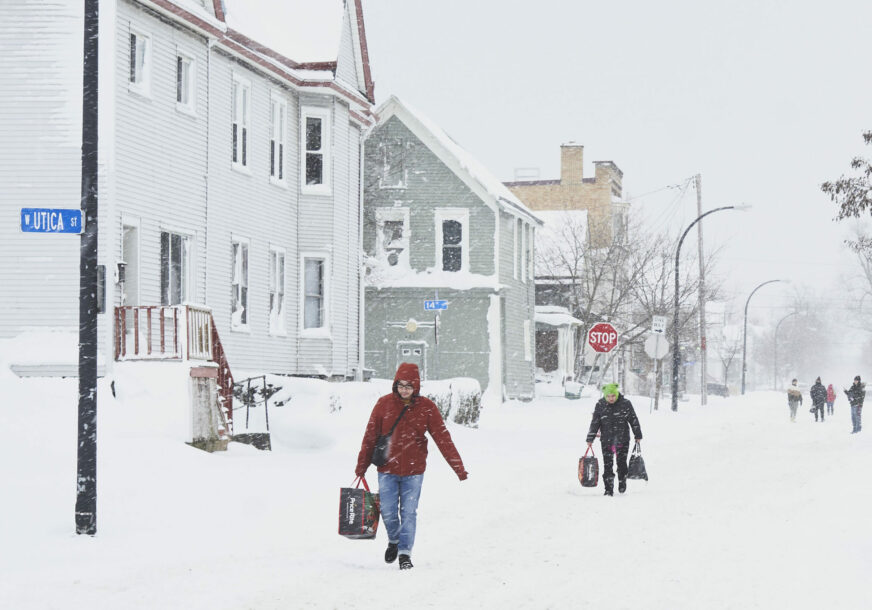 Ljudi hodaju ulicom zatrpanom snijegom