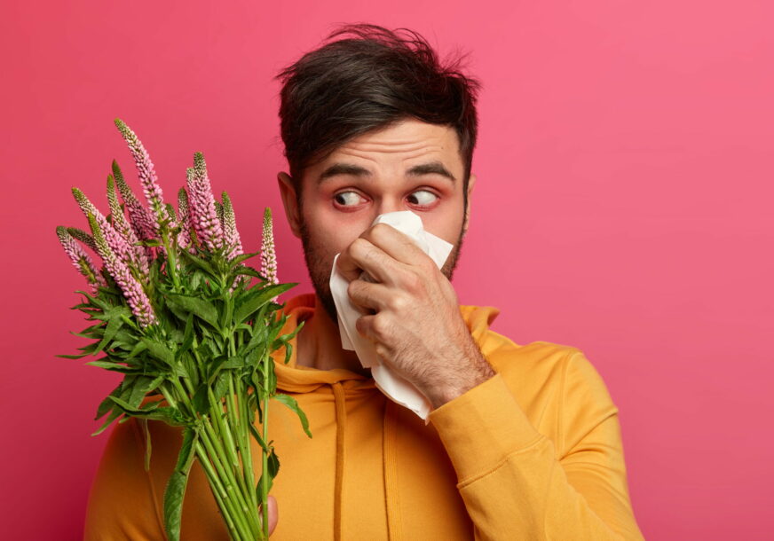 Muškarac, alergičan na polen, drži u ruci maramicu