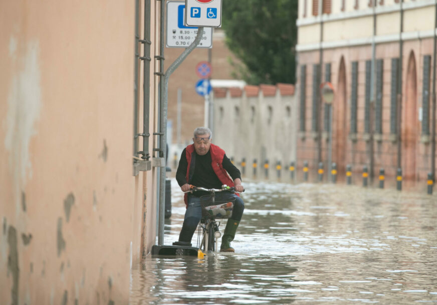 Čovjek vozi bicikl kroz poplavu
