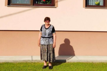 Žena stoji ispred kuće