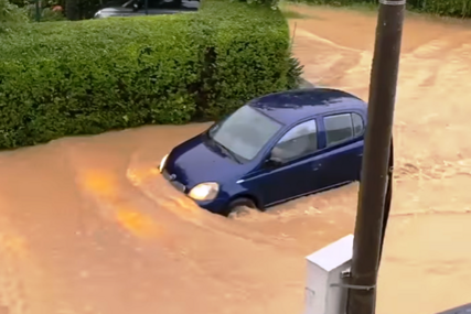Automobil prolazi kroz poplavljenu ulicu