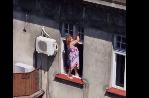 Žena pere prozor na zgradi