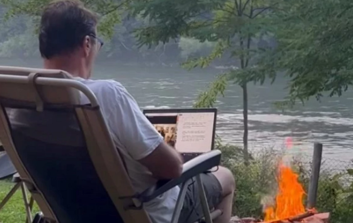 Čovjek sjedi u stolici pored vatre pored rijeke