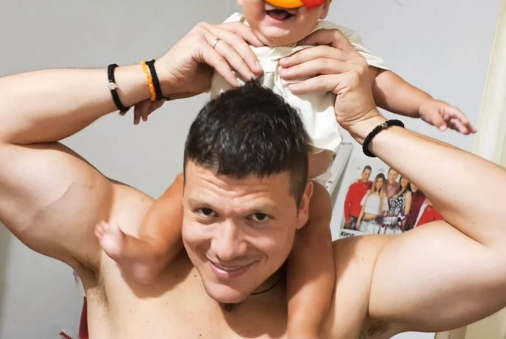 Muškarac drži bebu na vratu