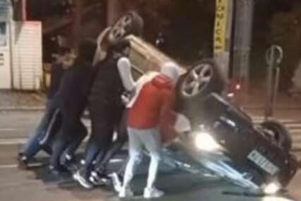 (VIDEO) DRAMATIČNA SCENA Auto završio na krovu nakon nesreće, mladići pokušavaju da ga okrenu nasred puta