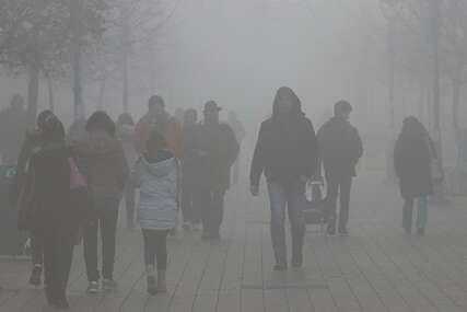 Ljudi hodaju kroz smog