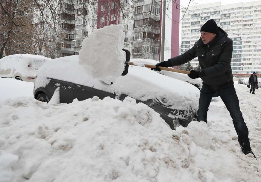 Čovjek čisti snijeg sa auta