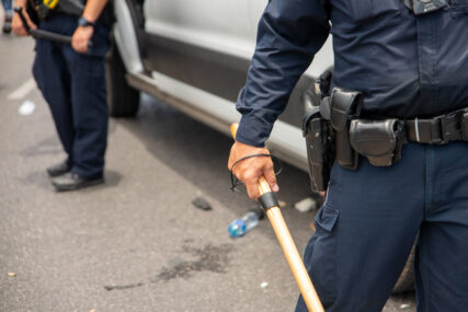 policajac drži palicu u ruci