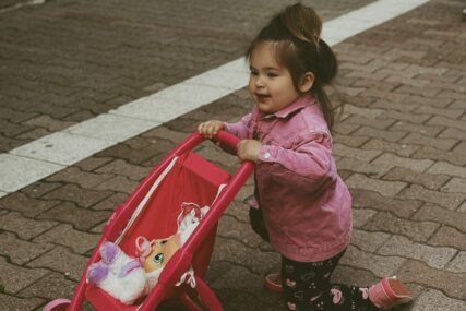 djevojčica vozi dječija kolica za bebu