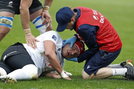 doktor ukazuje pomoć povrijeđenom sportisti