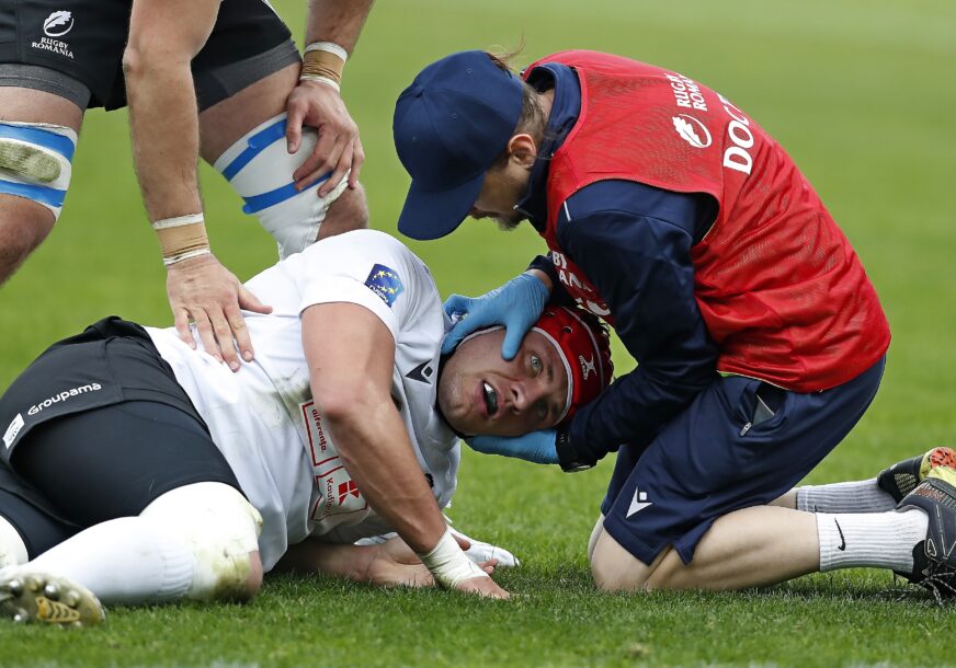 doktor ukazuje pomoć povrijeđenom sportisti