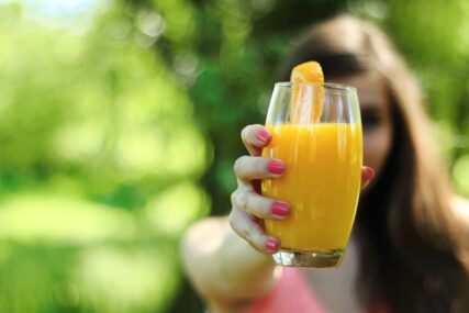 Djevojka drži čašu soka od narandže