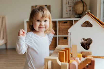 djevojčica se igra sa drvenim igračkama