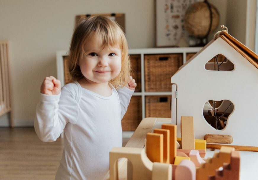 djevojčica se igra sa drvenim igračkama