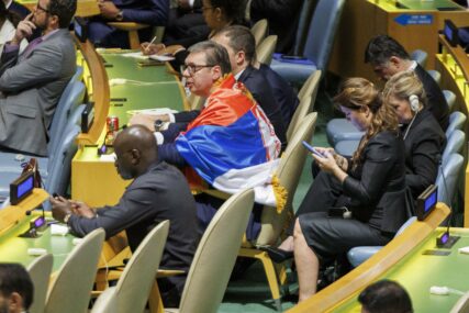 Vučić sjedi zagrnut zastavom