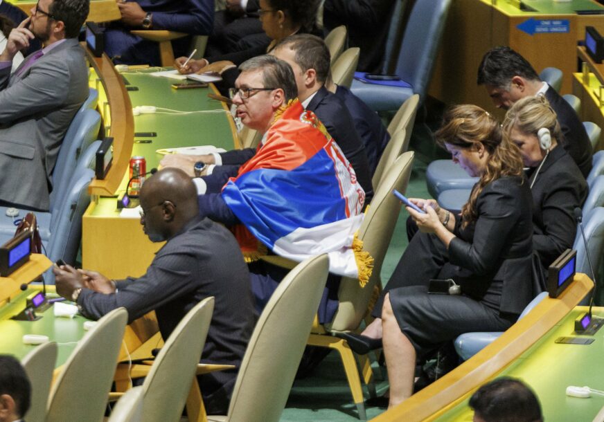 Vučić sjedi zagrnut zastavom