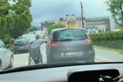 (VIDEO) POTEZ VOZAČA IZAZVAO LAVINU Čovjek u invalidskim kolicima se drži i kreće uz automobil, pljušte komentari