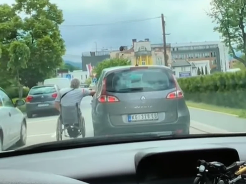 Čovjek u invalidskim kolicima se drži za automobil
