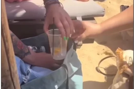 Turistkinja mućka piće na plaži