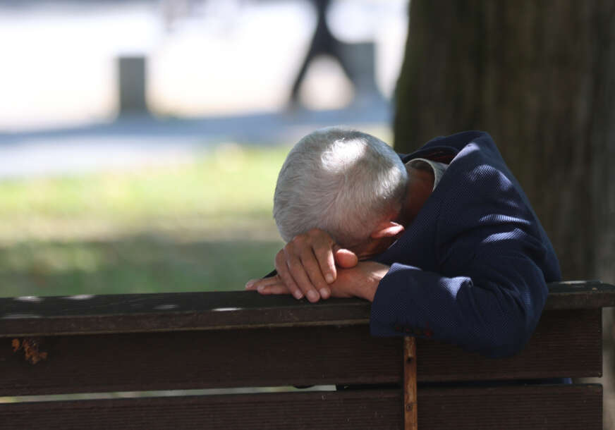 penzioner odmara na klupi u parku 
