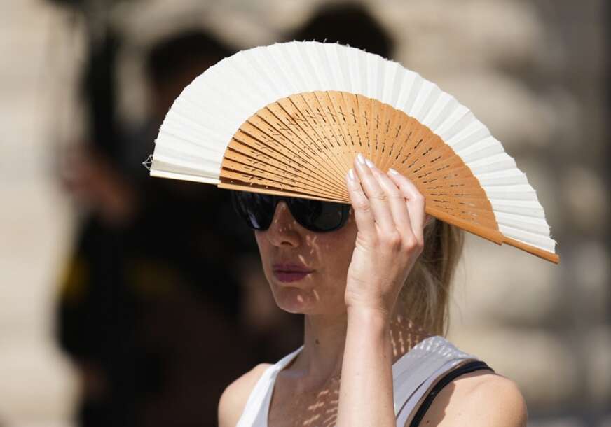 žena se lepezom štiti od sunca